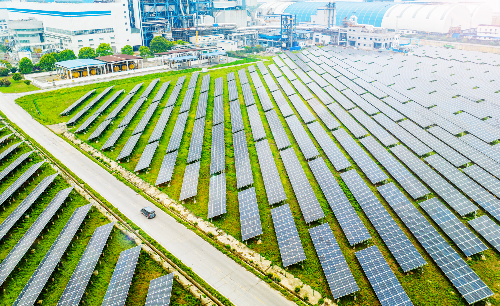 A large solar field with green grass growing between the panels